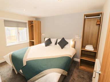 A bedroom with a double bed two wooden open wardrobes and a window at Bryn in Bethesda