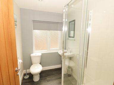 A bathroom with a toilet sink window with blind and a glass shower at Bryn in Bethesda