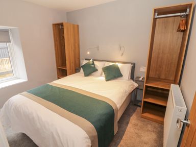 A bedroom with a double bed flanked by wooden wardrobes and bedside tables at Annest in Bethesda