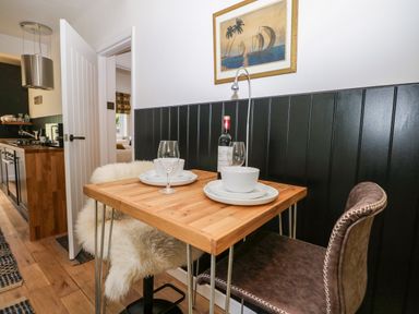 A small wooden dining table with two place settings and a bottle of wine in a kitchen area at Kub House in Wigginton Hertfordshire
