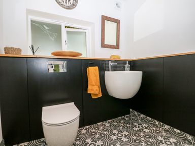 A bathroom with a toilet a sink a mirror and patterned floor tiles at Kub House in Wigginton Hertfordshire