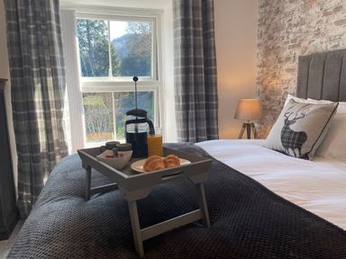 A bedroom with a bed tray holding coffee, croissants, and orange juice at 7 Castle Terrace in Dolwyddelan