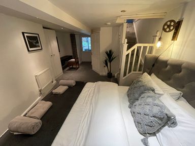 A bedroom with a bed with pillows and towels three doors a chair a desk and stairs at 7 Castle Terrace in Dolwyddelan