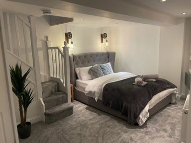 A bedroom with a double bed beside a staircase and a potted plant at 7 Castle Terrace in Dolwyddelan