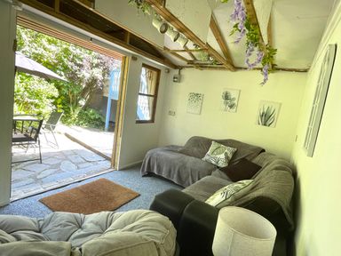 A living room with sofas pillows lamp and wall art opening to a patio with outdoor chairs and umbrella at 7 Castle Terrace in Dolwyddelan