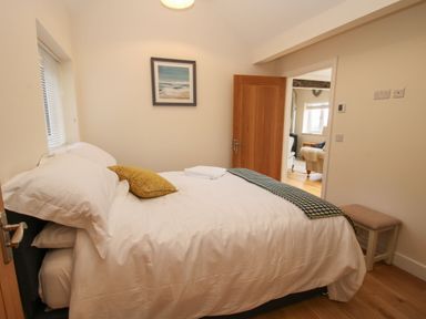 A bedroom with a bed a pillow and a blanket a stool and a painting on the wall at Border View Lodge in Llandrinio