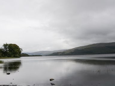 A lake with hills in the background and trees on the left at Millmore Cabin in Killin