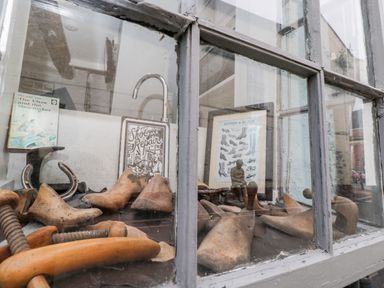 A window display with wooden shoe lasts and shoemaking tools at Cobblers Cottage in Upton Upon Severn