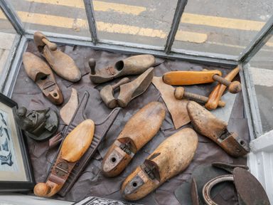 A collection of wooden shoe lasts and cobbler tools displayed on a leather surface in a window at Cobblers Cottage in Upton Upon Severn