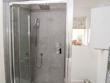 A bathroom with a glass shower enclosure and grey tiles at Cobblers Cottage in Upton Upon Severn