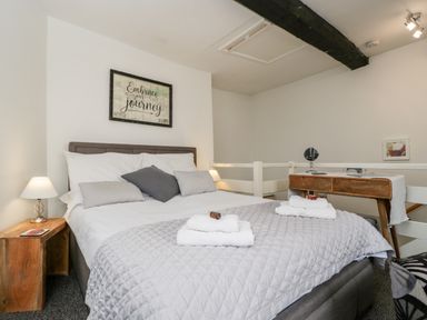 A bedroom with a double bed side tables a wooden desk and framed artwork at Cobblers Cottage in Upton Upon Severn