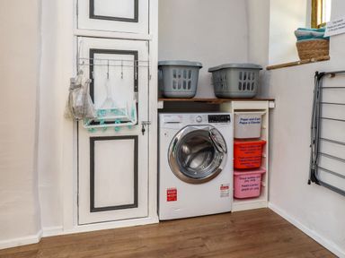A laundry room with a washing machine laundry baskets and recycling bins at Bwthyn Gwyn Ty'n Y Pant in Boduan near Nefyn