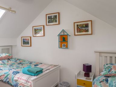 A bedroom with two single beds with patterned bedding a small nightstand with a lamp and framed pictures on the wall at Bwthyn Gwyn Ty'n Y Pant in Boduan near Nefyn