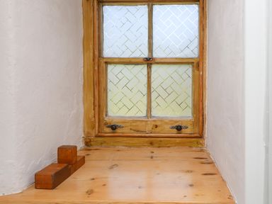 A small wooden window with patterned glass above a wooden shelf with wooden blocks on it at Bwthyn Gwyn Tyn Y Pant in Boduan near Nefyn