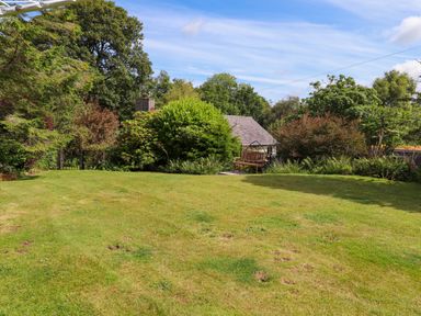 A garden with grass lawn trees bushes and a wooden bench at Bwthyn Gwyn Ty'n Y Pant in Boduan near Nefyn