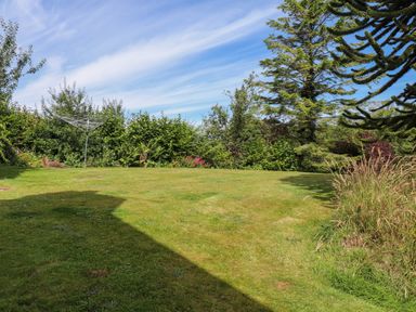 A grassy garden area with a rotary clothesline and trees at Bwthyn Gwyn Ty'n Y Pant in Boduan near Nefyn