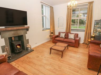 A living room with leather sofas coffee table fireplace and television at Yr Hen Ysgol The Old School in Prenteg