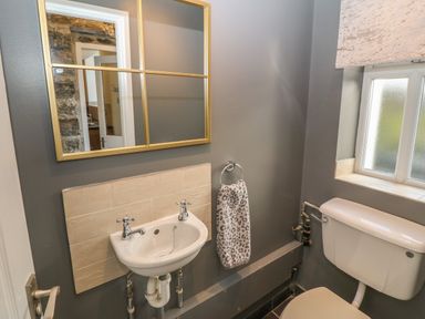 A small bathroom with a sink a mirror a towel ring with a towel a toilet and a frosted window at Yr Hen Ysgol The Old School in Prenteg