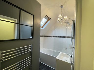 A bathroom with a bathtub shower sink mirror and towel rack at Yr Hen Ysgol The Old School in Prenteg