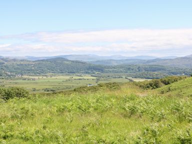 A landscape with hills trees and fields under a blue sky at Yr Hen Ysgol The Old School in Prenteg