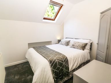 A bedroom with a bed two pillows a bedside table a skylight window and a wardrobe at Yr Hen Ysgol The Old School in Prenteg