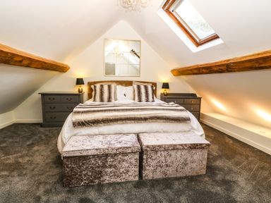 A bedroom with a bed two bedside tables with lamps a skylight window and a mirror at Yr Hen Ysgol The Old School in Prenteg