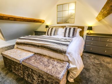 A bedroom with a bed pillows blanket two bedside tables with lamps and a chest of drawers at Yr Hen Ysgol The Old School in Prenteg