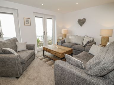 A living room with three grey sofas and a wooden coffee table at The Sandy Bee in Benllech