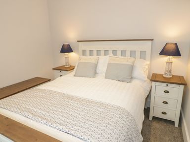 A bedroom with a double bed two bedside tables and two lamps at The Sandy Bee in Benllech