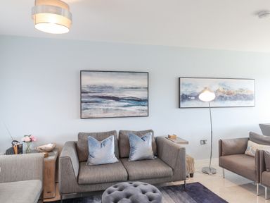 A living room with two grey sofas blue pillows a floor lamp and framed art on the wall at Chandlers Retreat in Newport Pembrokeshire