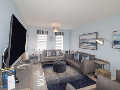 A living room with two sofas a large rug and a wall-mounted television at Chandlers Retreat in Newport Pembrokeshire
