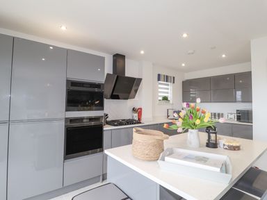 A kitchen with grey cabinets an island with flowers and a basket at Chandlers Retreat in Newport Pembrokeshire