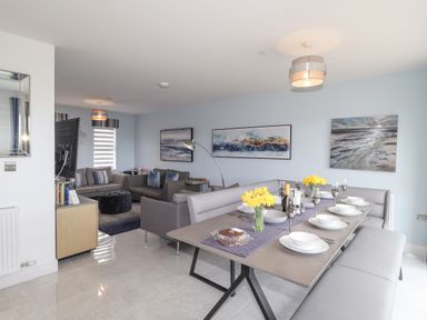A dining area with a table set for six and a living room with two sofas and a TV at Chandlers Retreat in Newport Pembrokeshire