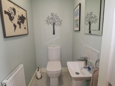 A bathroom with a toilet a sink a towel a radiator and wall decorations at Chandlers Retreat in Newport Pembrokeshire