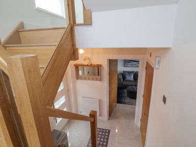 A hallway with wooden stairs leading down to a door opening into a room with a sofa at Chandlers Retreat in Newport Pembrokeshire