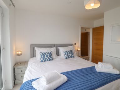 A bedroom with a double bed blue cushions white towels bedside tables and lamps at Chandlers Retreat Newport Pembrokeshire