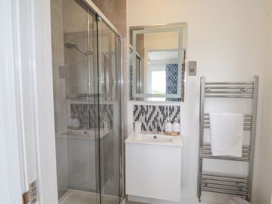 A bathroom with a glass shower enclosure a white sink vanity and a towel radiator at Chandlers Retreat in Newport Pembrokeshire