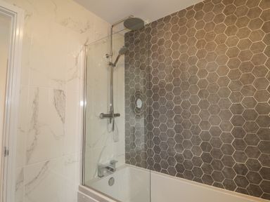 A bathroom with bathtub glass shower screen and hexagonal tile wall at Chandlers Retreat Newport Pembrokeshire