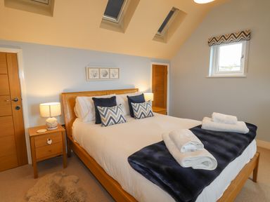 A bedroom with a wooden bed with pillows and towels on a blanket at Chandlers Retreat in Newport Pembrokeshire