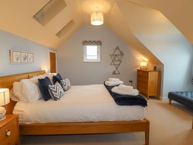A bedroom with a wooden bed with pillows and folded towels a wooden dresser and a blue bench at Chandlers Retreat in Newport Pembrokeshire