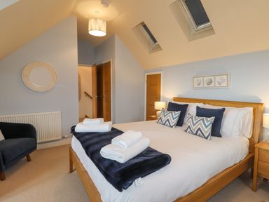 A bedroom with a wooden bed white bedding blue pillows and blankets bedside tables and lamps at Chandlers Retreat in Newport Pembrokeshire