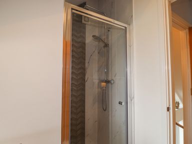 A shower with glass door and tiled walls in a bathroom at Chandlers Retreat in Newport Pembrokeshire