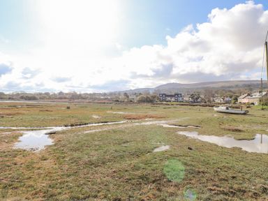 A marshy field with puddles and a boat near houses and hills at Chandlers Retreat in Newport Pembrokeshire