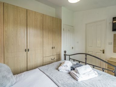 A bedroom with a metal bed frame folded towels on the bed wooden wardrobes and two white doors at Lakeview Lodge in South Lakeland Leisure Village