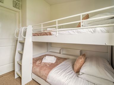A bedroom with white bunk beds with pink blankets and pillows at Lakeview Lodge in South Lakeland Leisure Village