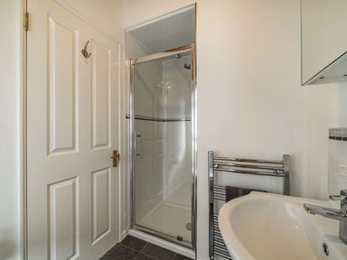 A bathroom with a white door a glass shower enclosure a white sink and a chrome towel rail at Lakeview Lodge in South Lakeland Leisure Village