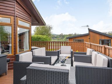 An outdoor patio with black wicker seating and a glass table with a bottle at Lakeview Lodge in South Lakeland Leisure Village