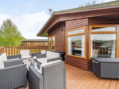 An outdoor patio with wicker seating and a glass table at Lakeview Lodge in South Lakeland Leisure Village