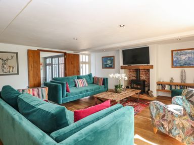 A living room with green sofas a wooden coffee table a fireplace and a television at The Barn Tunstead near Hoveton & Wroxham