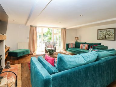 A living room with blue and green sofas a wooden coffee table and large windows at The Barn Tunstead near Hoveton & Wroxham